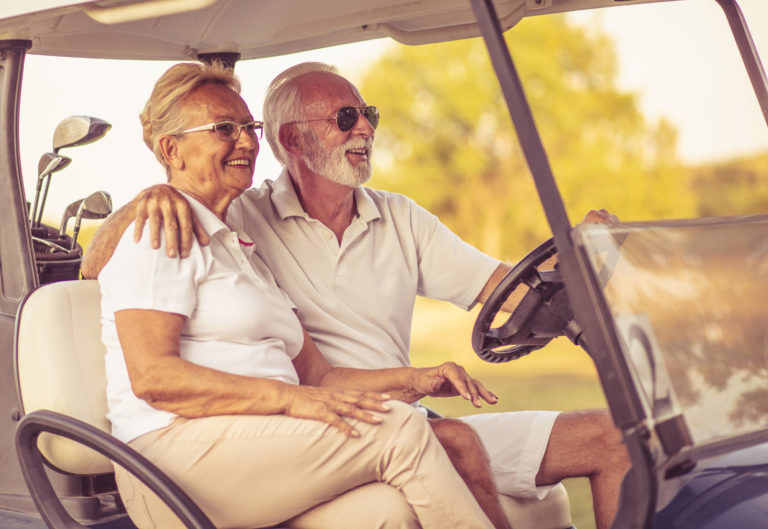 Golfers couple are riding in a golf cart and talking.